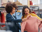 Two women examine a pink sweater